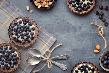Top view on wholegrain blueberry tarts with vanilla cream on dark