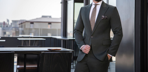 Man in expensive custom tailored suit standing and posing outdoors on balcony