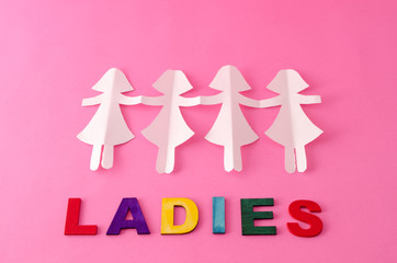 Paper doll chain and ladies made from colorful letters on pink background