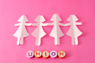 Paper doll chain and union made from colorful letters on pink background