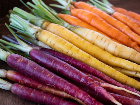 Close up of bunch of rainbow carrots prepped for cooking, sorted by color diagonally
