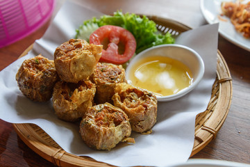 Hoi Jo, Crab jujube or Deep Fried Crab Meat Rolls, one of asian traditional food, serve on paper and basket with sweet dipping sauce on side.