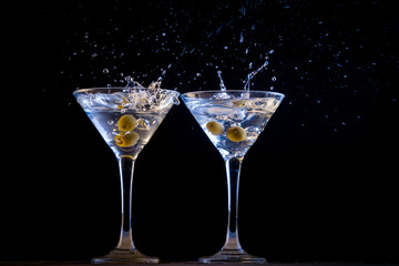 Two martinis with splashing olives