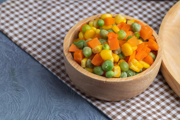 carrots corns and peas on wooden bowl