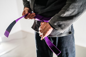 Close Up On Brazilian Jiu JItsu BJJ Fighter in a Gi Kimono Holding Purple Belt around his waist
