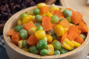 carrots corns and peas on wooden bowl