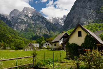 Obraz premium Garden and houses in Trenta Slovenia with Pihavec and Triglav mountain peaks in Triglav National Park Julian Alps in Spring