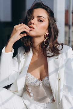 Fotografia do Stock: Beautiful young sexy woman, glamour girl in the white  elegant jacket, corset, suit, makeup pastel tone lipstick, nails on the  office balcony with the urban background.