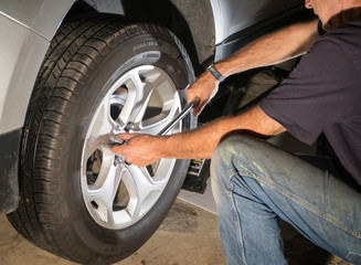 Man tightening lug nuts after replacing  car tire