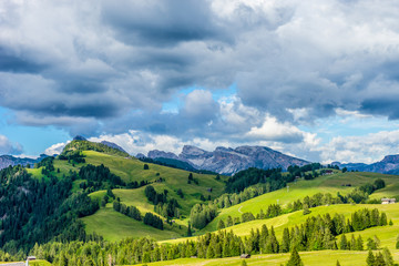 Naklejka premium Alpe di Siusi, Seiser Alm with Sassolungo Langkofel Dolomite, a large green field with a mountain in the background