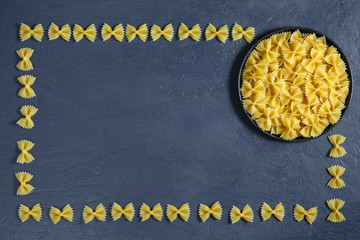 Border of a pile of pasta bow on dark black background with copyspace