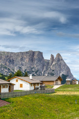 Alpe di Siusi, Seiser Alm with Sassolungo Langkofel Dolomite, a house with a mountain in the background