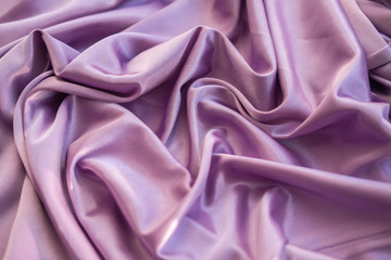 Obraz premium Close up pink fabric. The purple fabric is laid out waves. Fuchsia sateen fabric for background or texture.