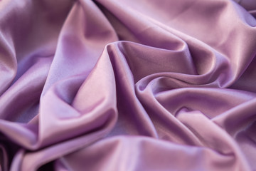 Close up pink fabric. The purple fabric is laid out waves. Fuchsia sateen fabric for background or texture.