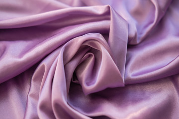 Close up pink fabric. The purple fabric is laid out waves. Fuchsia sateen fabric for background or texture.