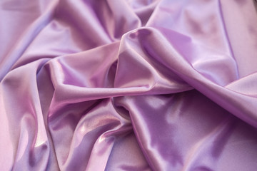Obraz premium Close up pink fabric. The purple fabric is laid out waves. Fuchsia sateen fabric for background or texture.