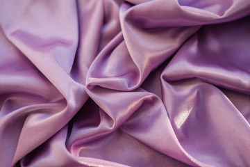 Close up pink fabric. The purple fabric is laid out waves. Fuchsia sateen fabric for background or texture.