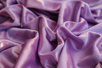 Close up pink fabric. The purple fabric is laid out waves. Fuchsia sateen fabric for background or texture.