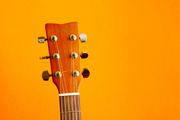 Head of acoustic guitar on orange background with copy space close up