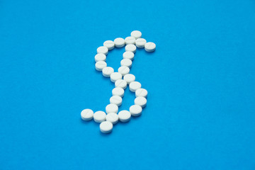 white pills in the shape of a dollar are scattered on a blue background