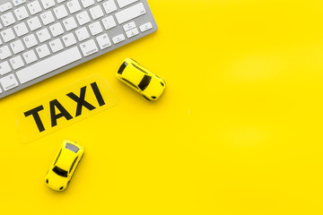 Taxi operator concept. Order taxi online. Sign ner car toy and keyboard on yellow background top view copy space