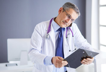 Male doctor writes notes on the clipboard in the hospital