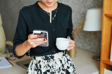 Woman drinking coffee and checking phone