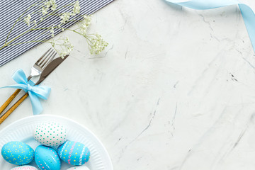 Easter table setting. Tableware and painted eggs on white stone background top view copy space