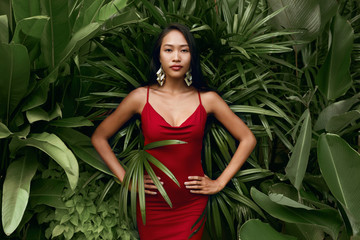 Fashion. Woman model in red dress with green palm leaves