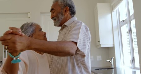 Side view of senior black couple dancing together in kitchen at comfortable home 4k