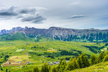 Obraz premium Alpe di Siusi, Seiser Alm with Sassolungo Langkofel Dolomite, a large green field with a mountain in the background