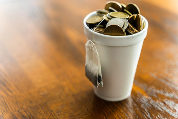 Styrofoam cup filled with coins and tea bag hanging outside