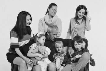 group of people on a white background: adults and children with toys sitting on the same couch