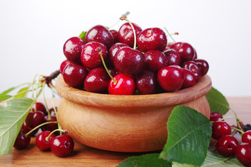 Sweet cherry fruits with leaves in a wooden bowl