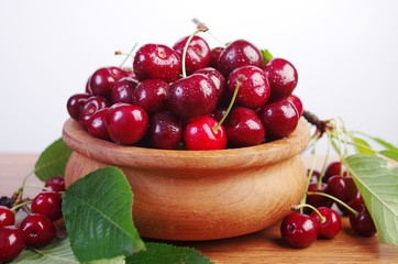 Sweet cherry fruits with leaves in a wooden bowl