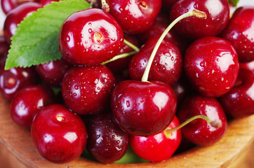 Sweet cherry fruits with leaves in a wooden bowl