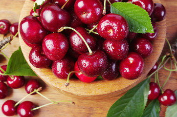 Sweet cherry fruits with leaves in a wooden bowl