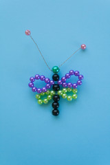 dragonfly made of beads, children's crafts on a blue background.