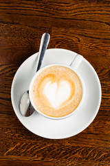 cappuccino with heart shape on the wooden table, top view