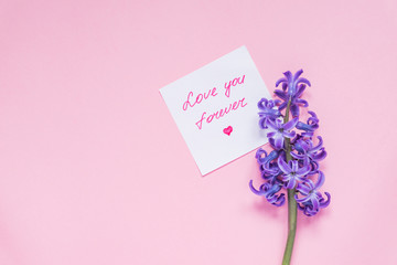 Love you forever paper tag and purple hyacinth flower on wooden table. Top view, miniml flat lay