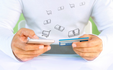 Male hands holding a credit card and using a mobile phone for online shopping.