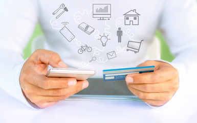 Male hands holding a credit card and using a mobile phone for online shopping.