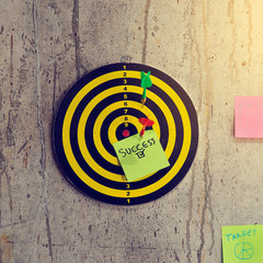Success word on colorful sticky notes with dart game on cement wall, business concept.