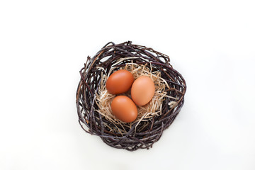 Easter! Chicken eggs in a nest with branches, agriculture. Easter eggs on the table in the nest. Beige Easter eggs. Eggs on a white background. Horizontal image.