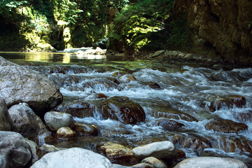 Clear water of the wild moutain river falling from the moss covered stones in the in Georgia