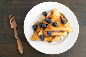 pancakes with syrup nuts and blueberries. on a white plate
