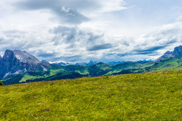Fototapeta premium Alpe di Siusi, Seiser Alm with Sassolungo Langkofel Dolomite, a large green field with a mountain in the background