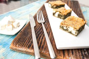 Strudel with spinach and ricotta on a dark wood background.