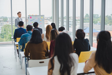 Asian male speaker is speaking at seminars and workshops to the people in the meeting.