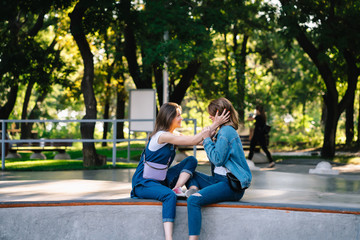 Fototapeta premium Two happy young girls sitting at the skate park